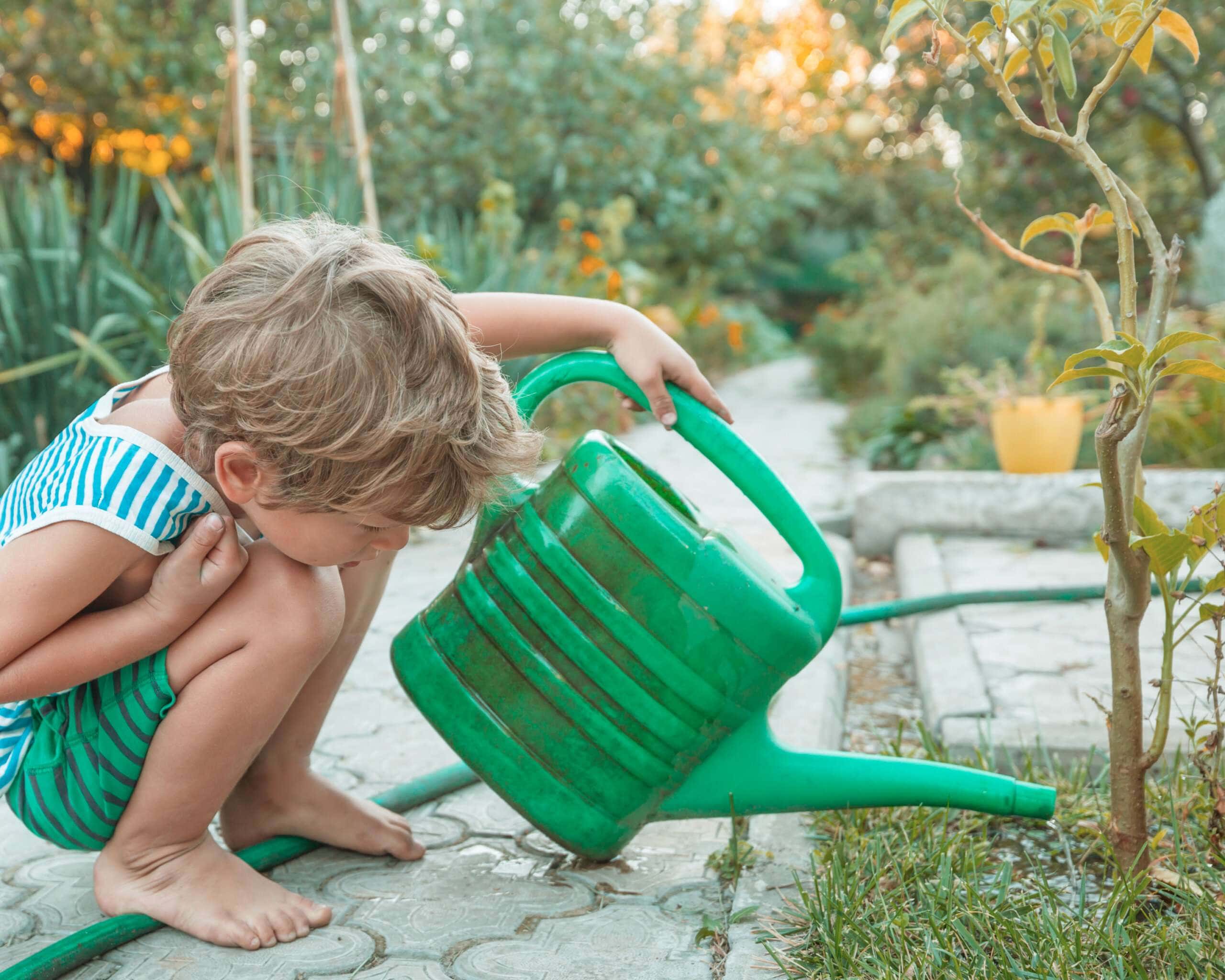 Child watering plant in a nature-based curriculum.