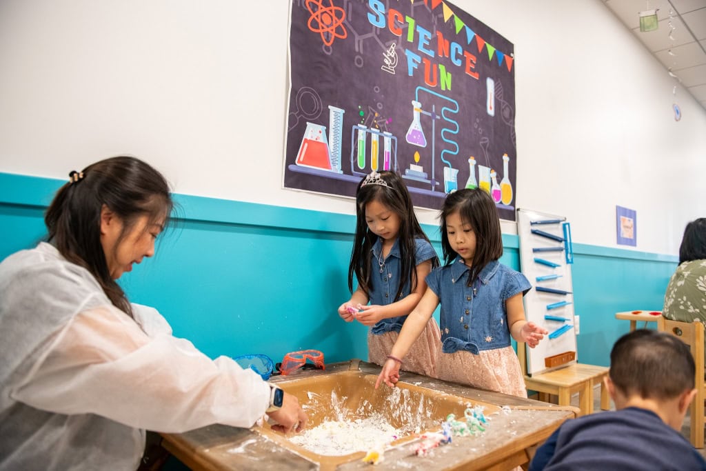 Young children testing floating and sinking objects during STEAM activity at Irvine preschool